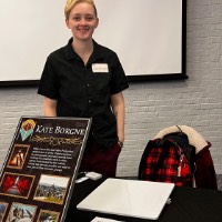 Kate Borgne stands behind their table to show work